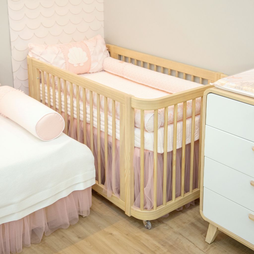 Berço de Bebê com o enxoval Rosa em um Quarto com decoração de menina.